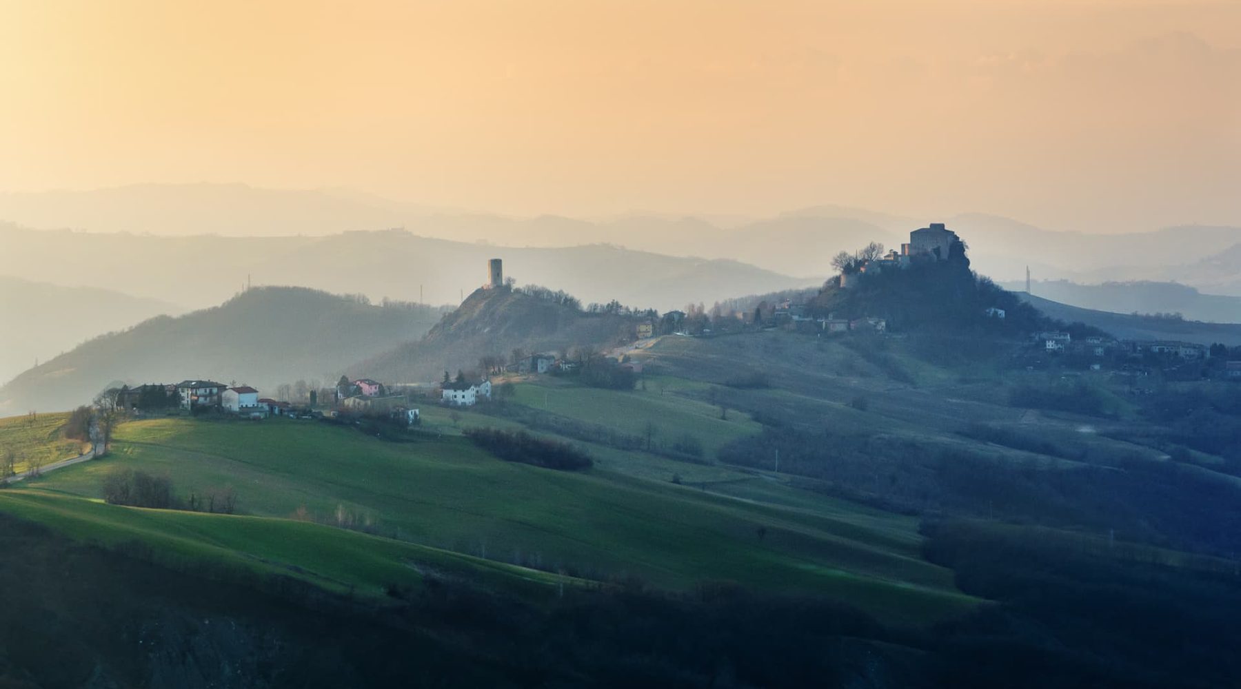 Le colline delle Terre di Matilde all'alba, con il castello di Rossena sullo sfondo