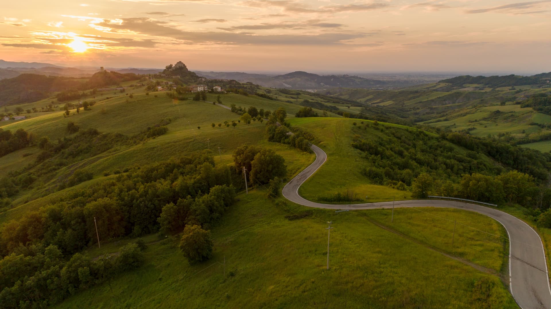 Le colline di Quattro Castella al tramonto, con il castello di Rossena sul crinale